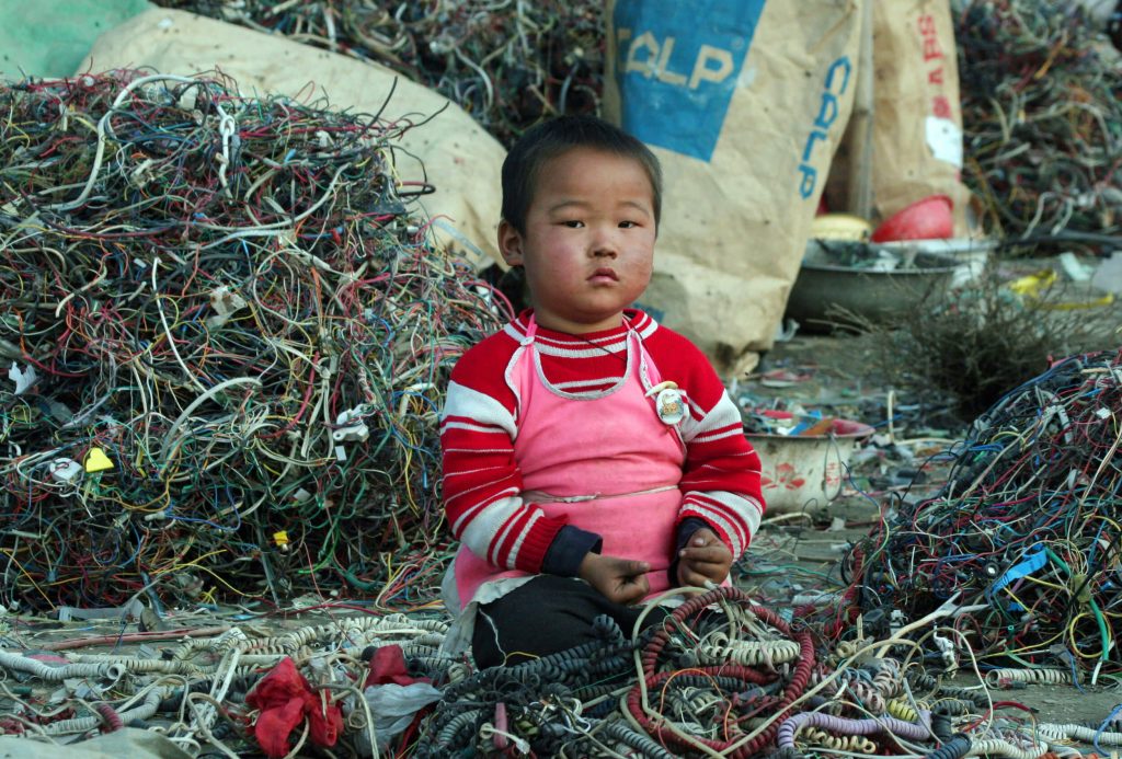 Photo - Infant sitting around electronic waste